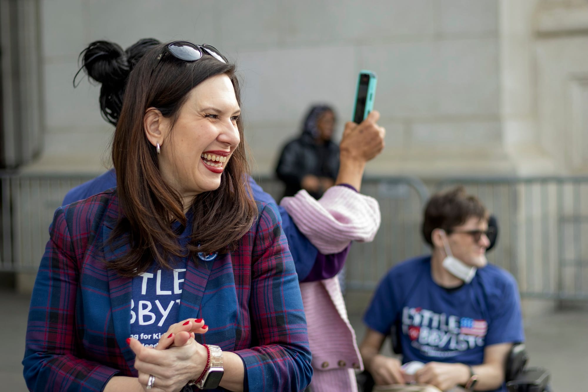 Laura, who has long hair and sunglasses pushed up on top of her head, smiles outside Union Station. Kody is to her right.