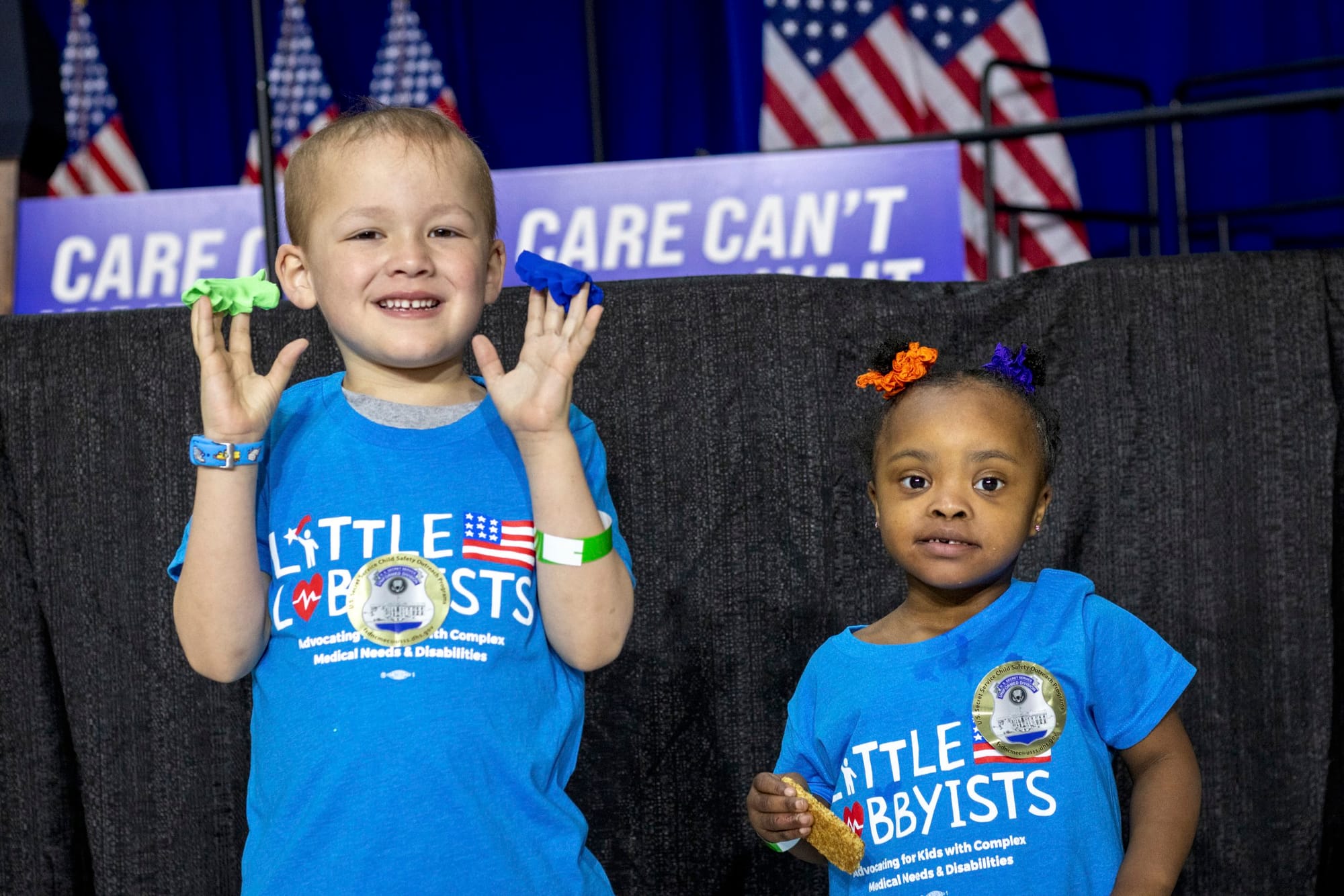Gabe and Destiny pose in front of the stage, which is all in blue and white with American flags.