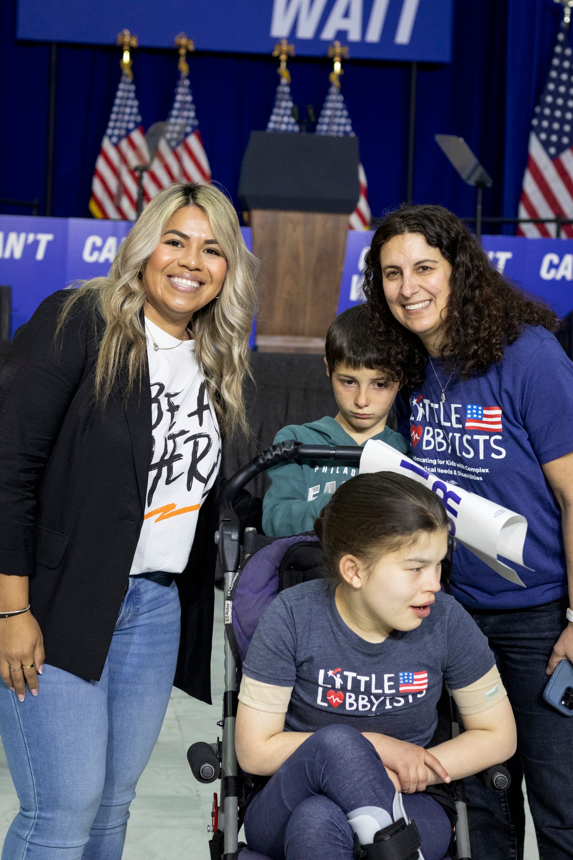 Jamie, her daughter Claire (who uses an adapted stroller) and son Ben pose in front of the stage, with Izzy, a careworker for the late Day Barkan.