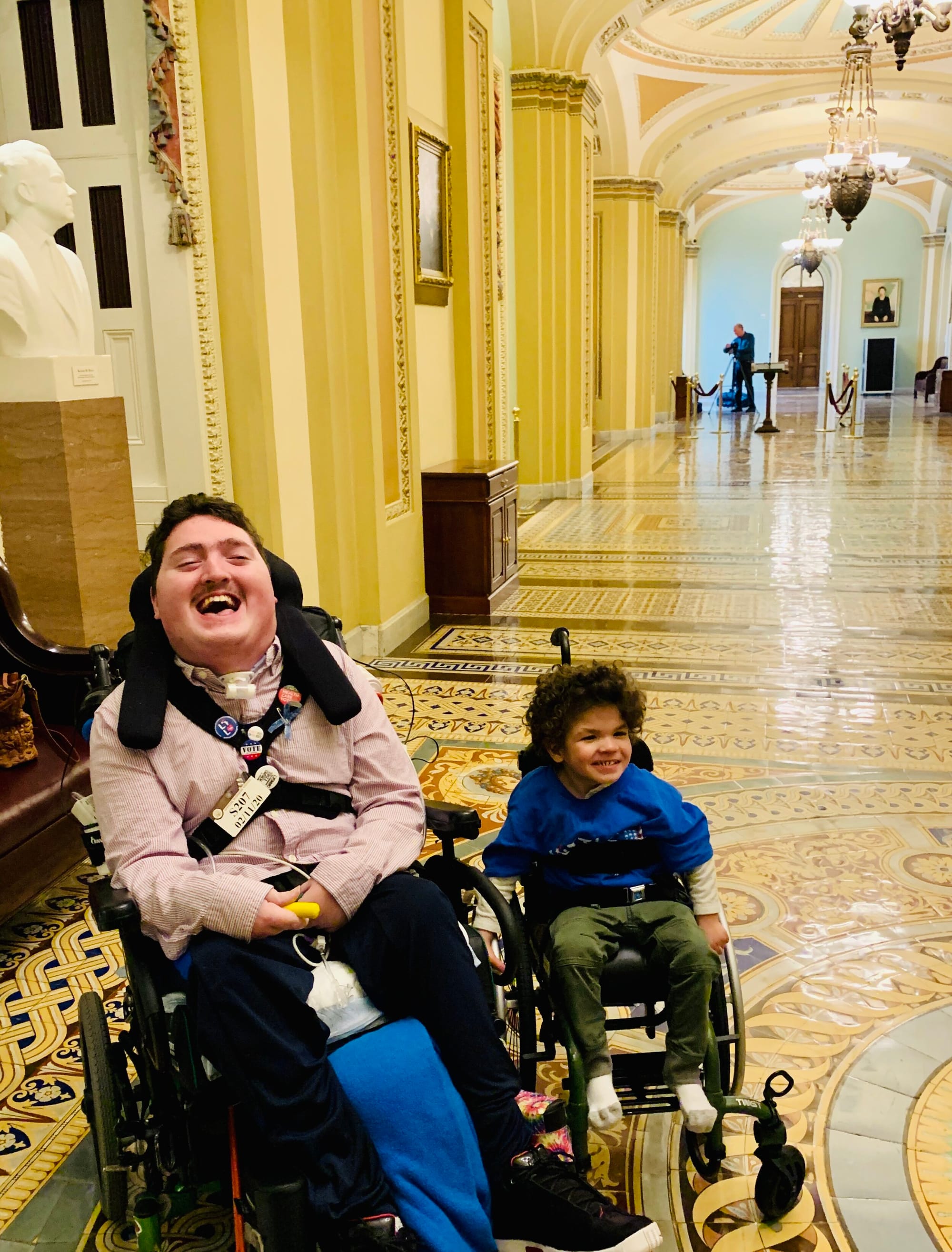 Two young men who are wheelchair users pose in a hallway of the U.S. Capitol after representing Little Lobbyists at a Senate press conference.