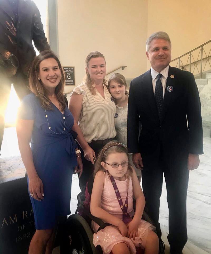 Little Lobbyists families pose in the halls of a House office building with a representative.