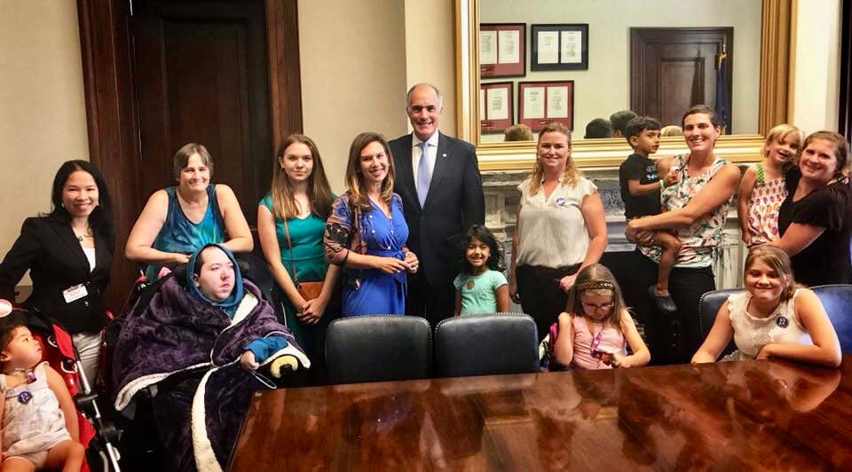 A group of Little Lobbyists families pose with a U.S. Senator after a meeting on health care.