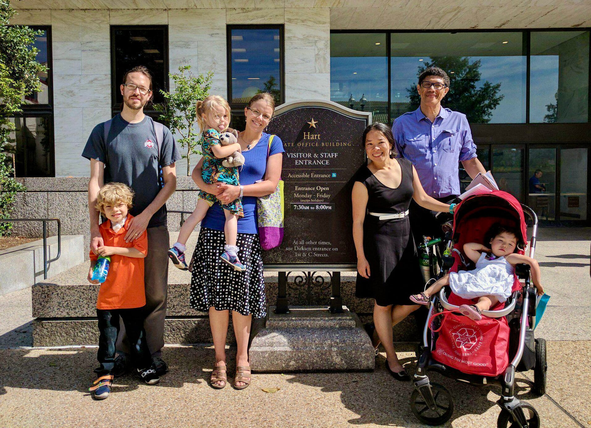 Several Little Lobbyists families pose outside the U.S. Hart Senate Office building, next to its sign.