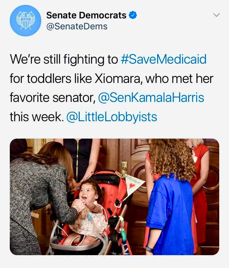 A toddler girl in a disability stroller greets a U.S. Senator.