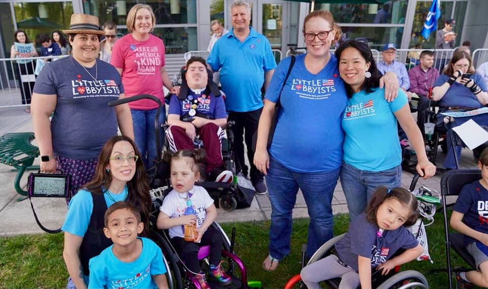 A group of Little Lobbyists families, wearing brightly colored LL t-shirts are photographed at a presidential candidate’s campaign rally.