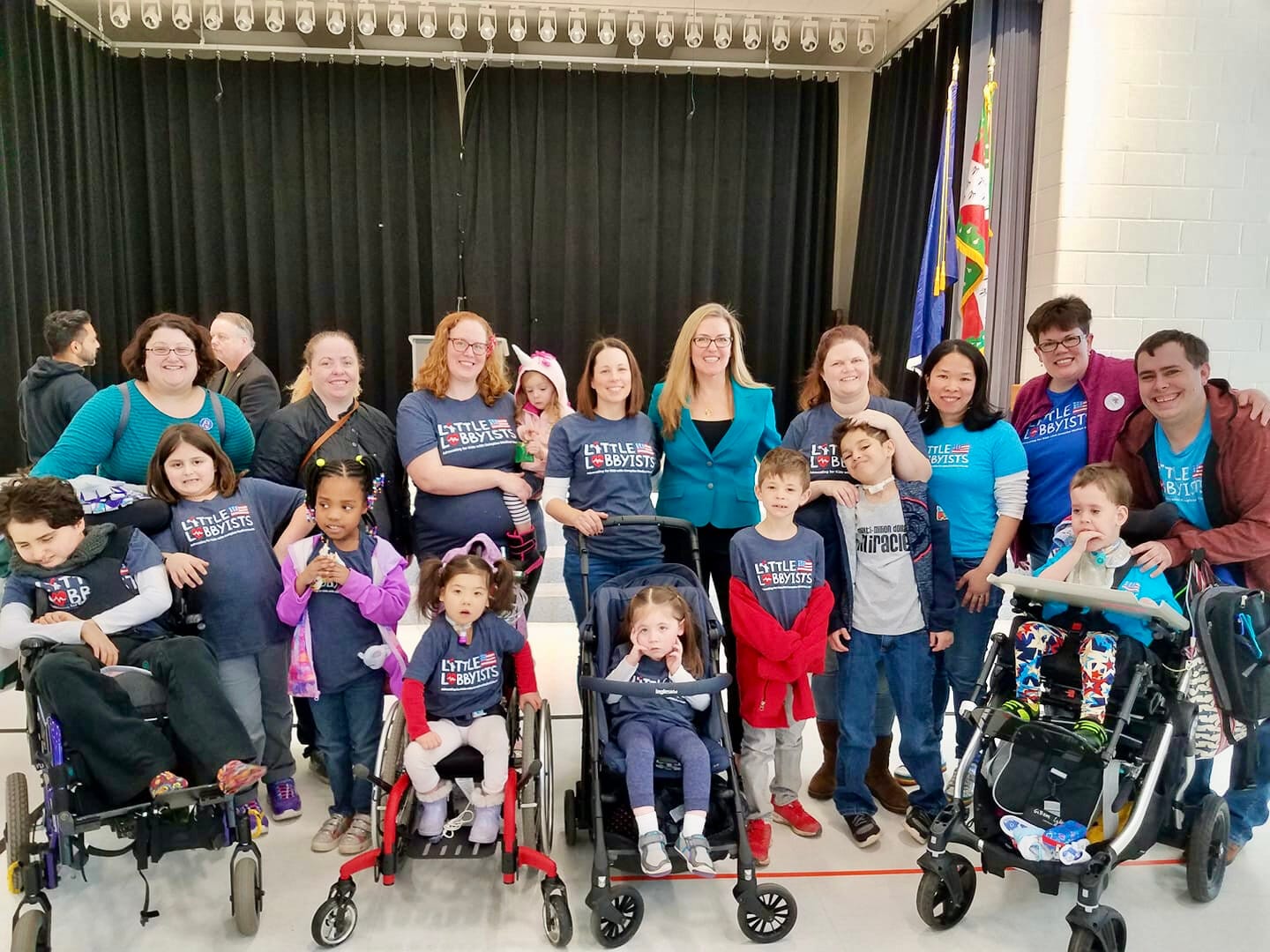 A large group of Little Lobbyists poses with a member of. Congress in front of curtains.