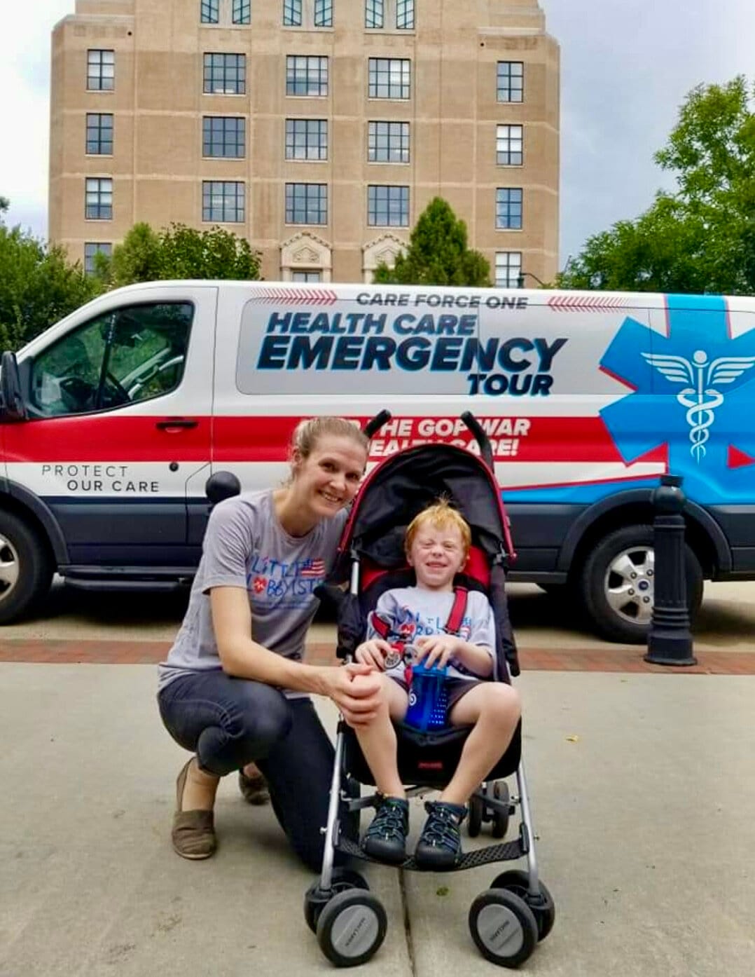A mom poses with her child (who uses a disability stroller) in front of an ambulance during a health care public service campaign.