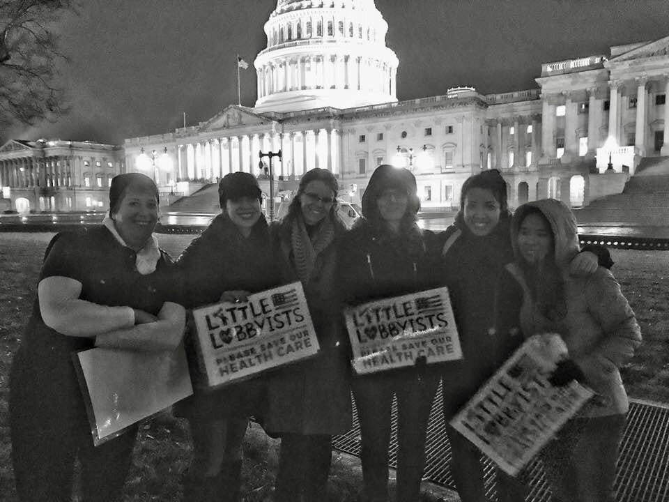 In a black and white photograph, several Little Lobbyists moms pose in front of the U.S. Capitol, during the early days of the efforts to save the Affordable Care Act.