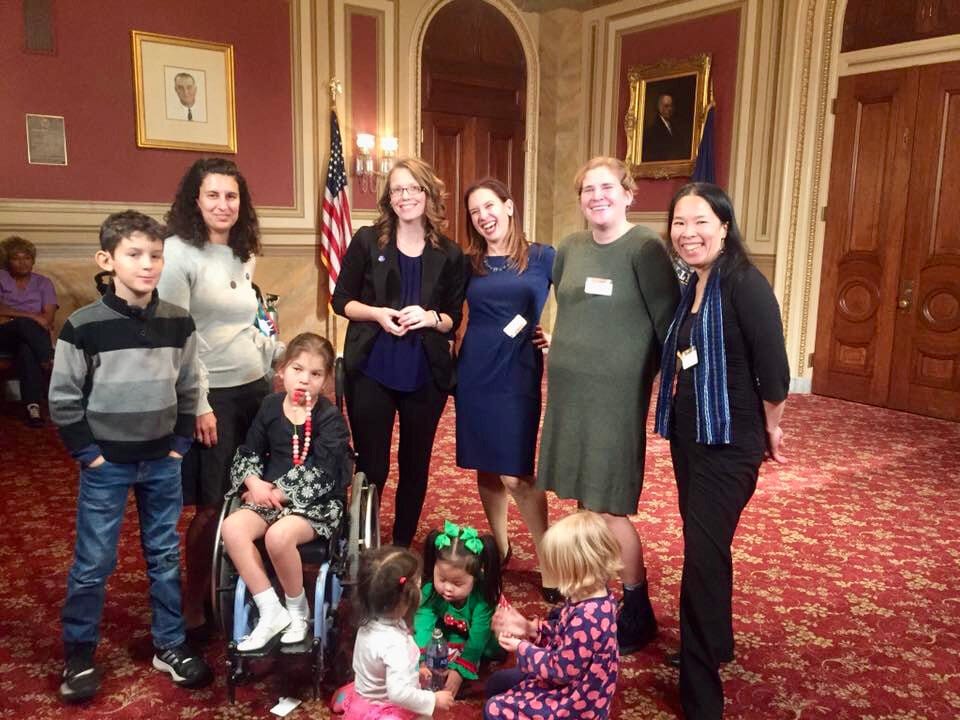 Members of Little Lobbyists pose for a photo in a beautifully decorated, red-accented room in the U.S. Capitol.