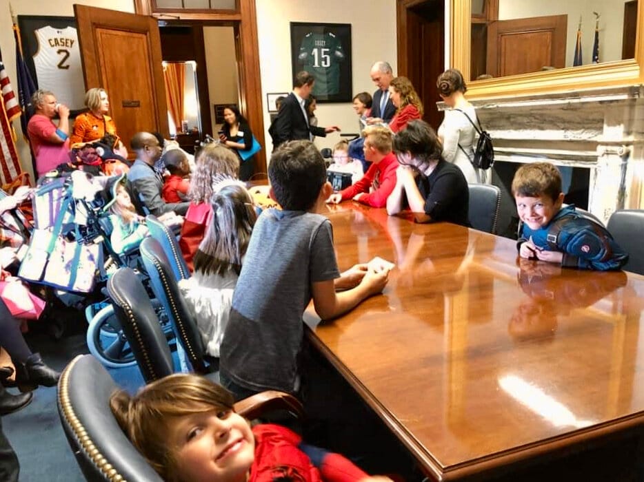 Little Lobbyists kids pile around a large conference table during a Halloween on the Hill day.