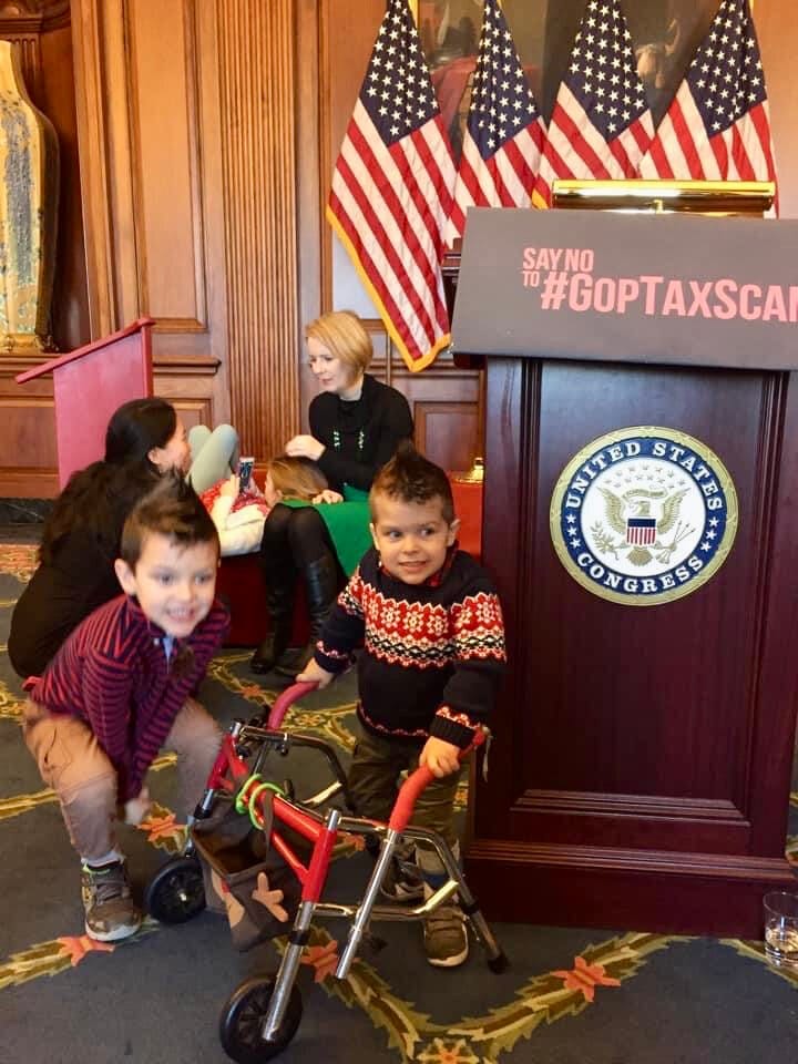 Two young boys play near a podium with a legislative seal. American flags are in the background.
