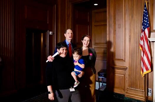 Little Lobbyists family poses with a U.S. Senator. An American flag stands to one side.