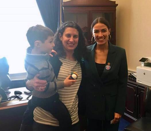 A mom holds her young son while they smile for the camera with a new member of Congress.