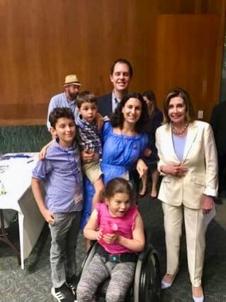 A Little Lobbyists family poses with the Speaker of the House in a wood-paneled meeting room.