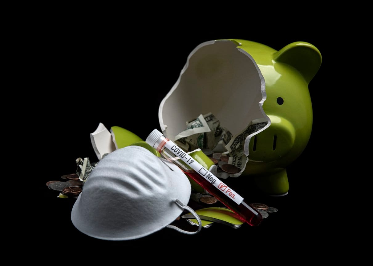 Broken piggy bank with an N95 mask and a vial that says COVID-19 positive in front of it