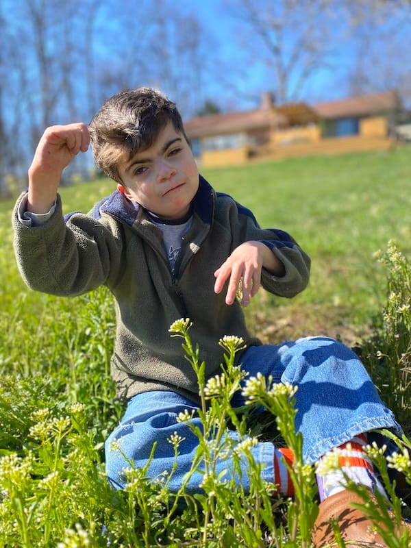 A smiling Charlie in a grassy field on a sunny day.